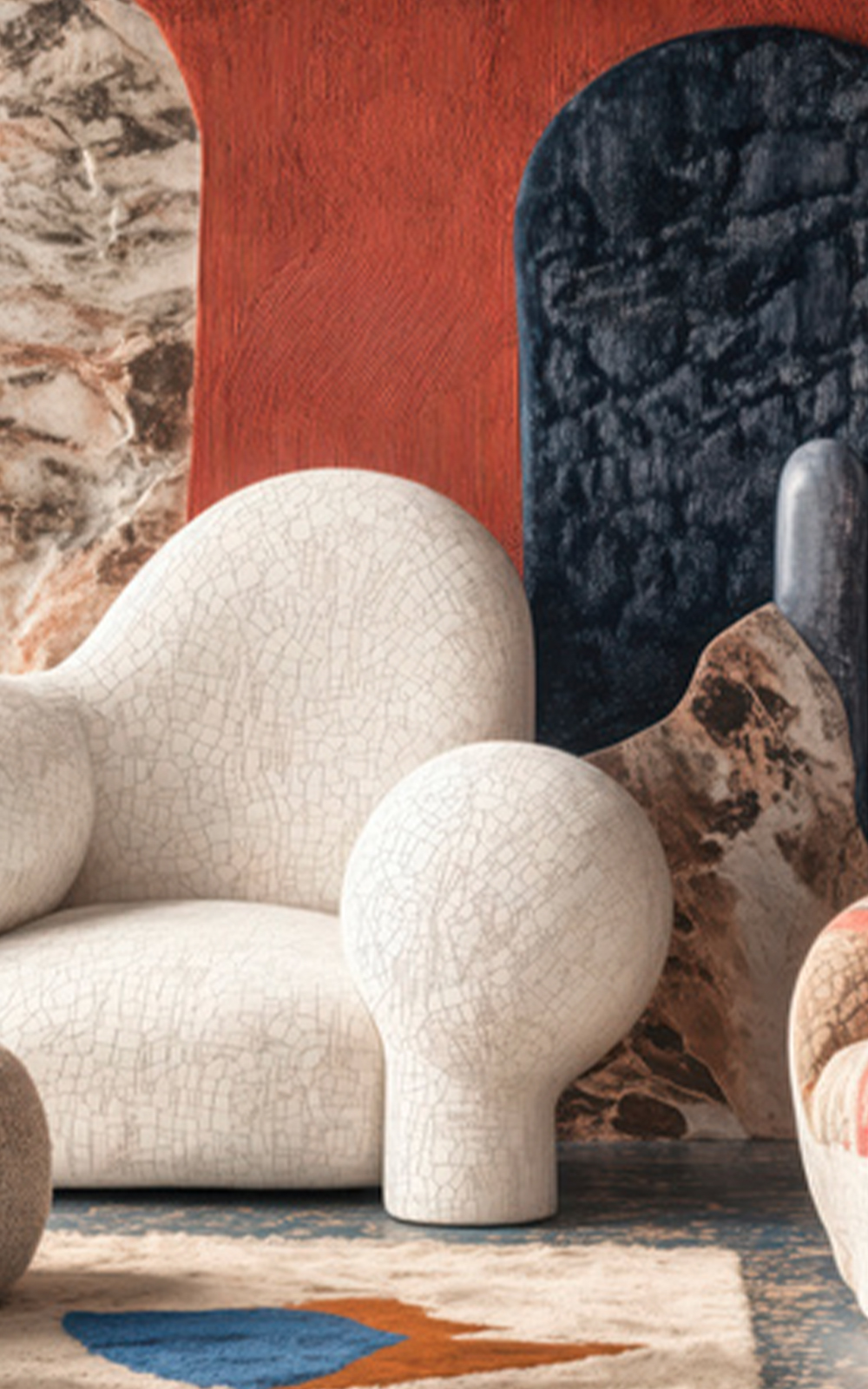 A modern interior features a sculptural, crackled white armchair with rounded shapes. The background has bold red, navy, and stone textures, highlighting the design. Part of a beige rug with geometric patterns is visible on the floor.