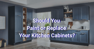 Modern kitchen with dark blue cabinets, white countertop, open shelving, and white tile backsplash. Large text in the center reads: "Should You Paint or Replace Your Kitchen Cabinets?.