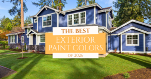 A large two-story house with blue exterior paint and white trim is surrounded by trees and a well-manicured lawn. Text overlay reads: “The Best Exterior Paint Colors of 2026.”.