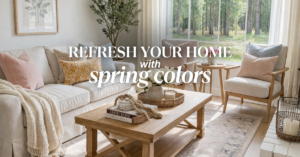 A bright living room with neutral furniture, pastel throw pillows, a wooden coffee table with decor items, large windows with sheer curtains, and green trees visible outside. Text reads: "Refresh your home with spring colors.