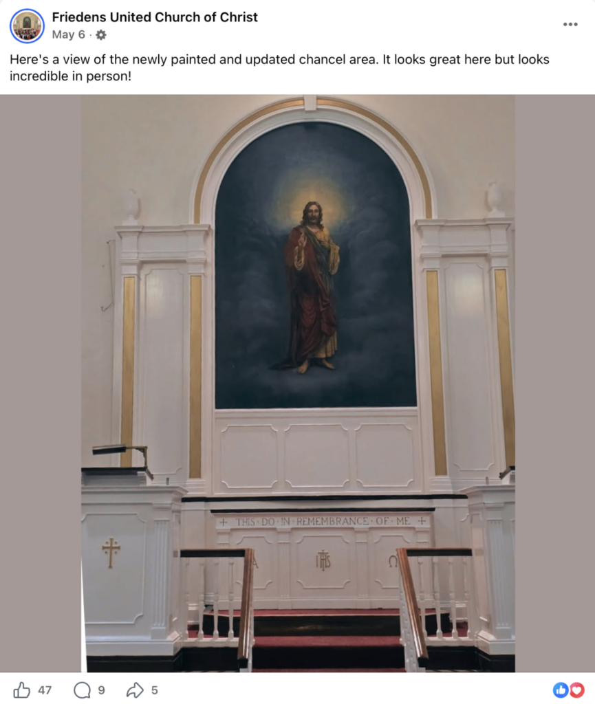 Interior view of a church chancel area featuring a large painting of Jesus with a glowing halo, surrounded by white walls, wood paneling, and a communion rail.