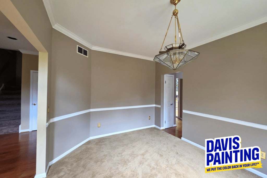 Empty beige dining room with crown molding, tan carpet, and a gold chandelier. To the right is a doorway to another room. “Davis Painting” logo appears in the bottom right corner.
